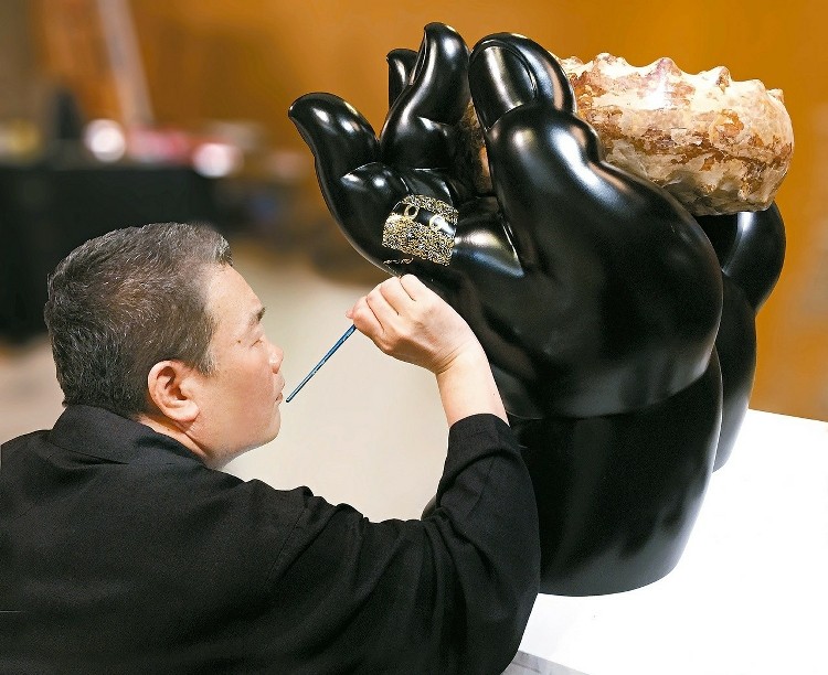 艺术总监李善单作画如练龟息大法。他用极细的笔，在佛手铜雕上画图腾。 铜雕不易上色，每一笔至少要重复四、五次。线极细，绝不能失手，下笔都得停止呼吸。